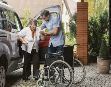 A friendly NEMT driver helping a senior patient into a wheelchair-accessible van at Diamond Care Transportation Also Apply to Drive for Diamond Care Transportation